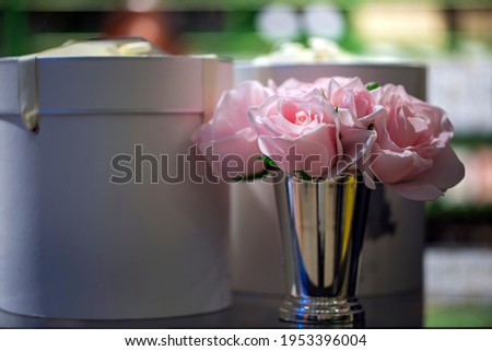 Unfocused blur Decorative artificial fake roses flowers in vase on a gift boxes. beautiful pink Bouquet in pots, home decor. abstract romance background, pastel and soft flower card. Selective focus
