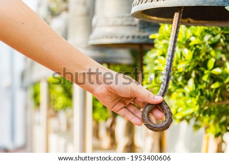 Woman hand rings the old bell for Make a wish in the Wat Saket Golden Mountain Temple famous , Golden Mount is a Buddhist temple in Pom Prap Sattru Phai district, Bangkok. Royalty-Free Stock Photo #1953400606