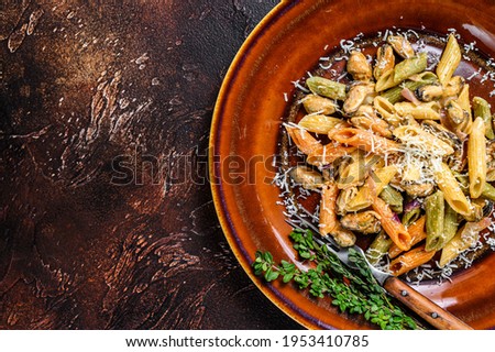 Seafood color Penne pasta in cream sauce on a plate. Dark background. Top view. Copy space