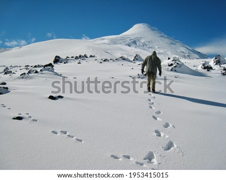 Man walking bravery in snow conditions up to the top of the mountain near Osorno volcano in Southern Chile. Concept for follow your path, isolated travel, free, freedom, challenge, motivational. Royalty-Free Stock Photo #1953415015