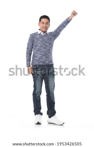 full length portrait of happy handsome young man hold arm hand  fist raised up gesture.posing in studio


