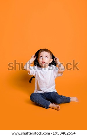 little child in jeans and a white t-shirt on a yellow background