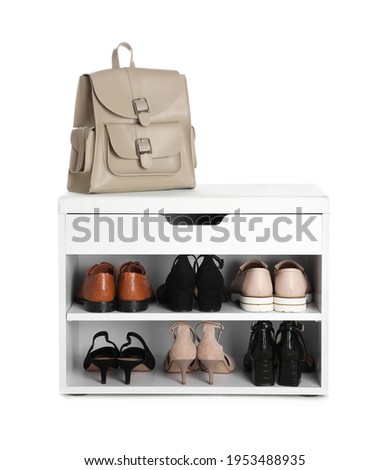 Stylish storage cabinet with different pairs of shoes and backpack on white background Royalty-Free Stock Photo #1953488935