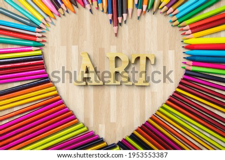 Education concept. High angle view of sharp color pencils shaped heart symbol with Art word
