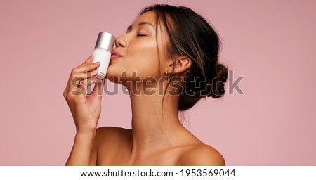 Attractive asian woman kissing a skincare product bottle. Female with best cosmetic product for skin. Royalty-Free Stock Photo #1953569044