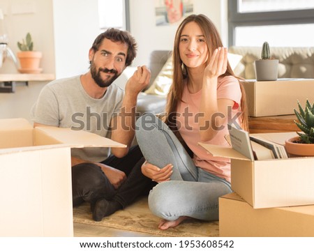 young couple making capice or money gesture, telling you to pay your debts!