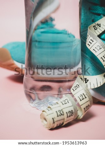 turquoise sneakers and a bottle of water on a pink background. The concept of a healthy lifestyle, daily training and following the figure .