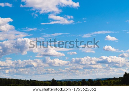 the sky is in voluminous clouds multiple above the horizon line of the treetops