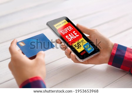 Closeup of man hands holding smartphone with shopping app and credit card, having good offer. Phone screen with super sale screen, webstore app on mobile phone, creative image