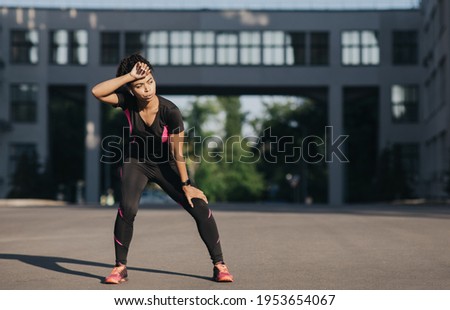 Workout break, active lifestyle and body care outdoor. Tired african american young slim lady in headphones breathing heavily and wiping sweat from forehead on town street in morning, empty space Royalty-Free Stock Photo #1953654067