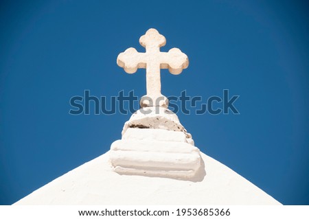 Close-up of a white cross from a church on the island of Naxos in Greece. In the background the blue sky without clouds