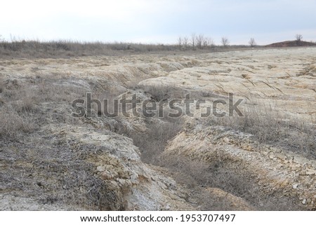a field of dry clay soil with a city in the background