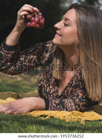 girl lying with a bunch of grapes in her hands