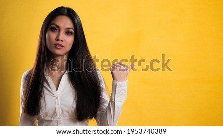 Young pretty woman points to something - studio photography