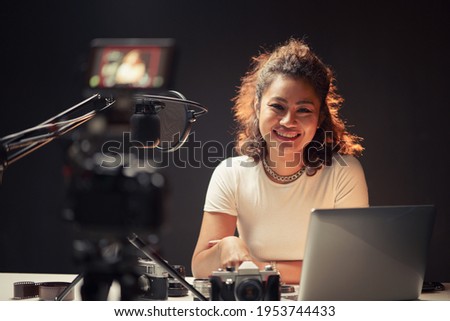 Product advice for podcaster. Smiling female review blogger smiling to camera while recording online shopping review. Concept online learning or social marketing.