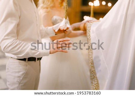 A priest in a white habit marrying the bride and groom in the church of St. Nicholas in Kotor 