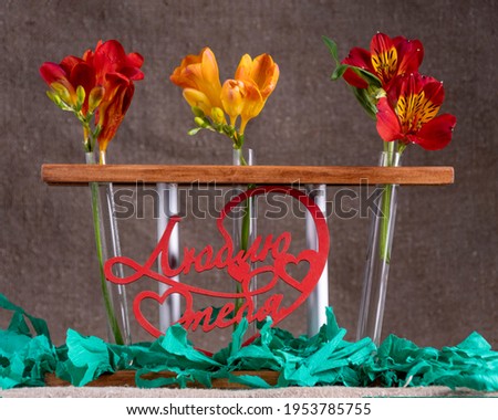 Composition flowers in test tubes, on a gray background with the inscription 
"I love you". apply as gift cards on a holiday.