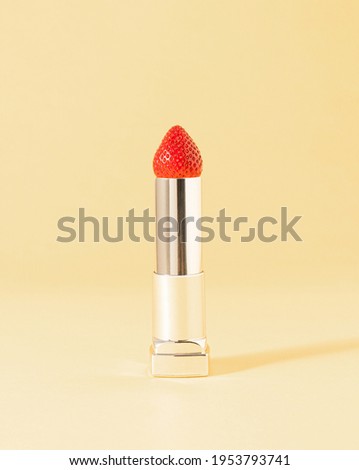 Creative composition made of silver lipstick and strawberry on pastel beige. Minimal natural cosmetics background.