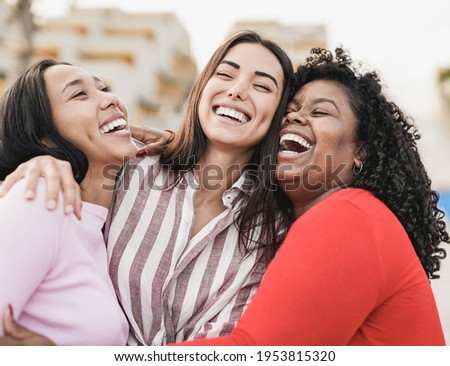 Happy latin women laughing and hugging each other outdoor in the city - Millennial girls and friendship concept Royalty-Free Stock Photo #1953815320