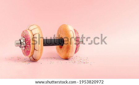 Creative concept for a healthy lifestyle.  Dumbbell with donuts on a pink background with copy space.
