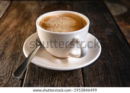  A cup of coffee on a saucer, on a wooden background.
