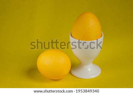 Postcard for Easter. Still life. Golden fabulous egg. Yellow egg. Yellow background. Minimalism. Monochrome. Close-up. With copy space for text. Horizontal format.