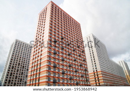 The view of new high-rise buildings with beautiful stripes of white orange brown balconies and areas for air conditioning on a clear sunny day, construction business investment.