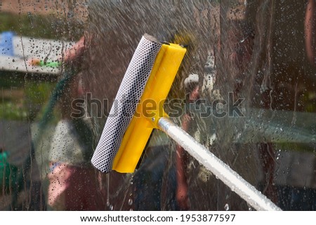 a man with a mop washes a large window in a wooden country house