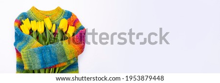 Bouquet of yellow tulips on the background of a multicolored knitted sweater, top view, bouquet of yellow tulips for women's day, spring flowers concept.
