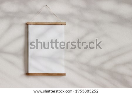 Blank wooden picture frame hanging on beige wall. Empty poster mockup for art display in sunlight. Minimal interior design.Palm leaves shadow overlay. Summer design. Copy space. No people.  Royalty-Free Stock Photo #1953883252