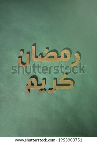 Ramadan Kareem greeting message: "May the month of Ramadan be blessed to you!" Golden arabic 3d letters with shadows on a dark green background. Flat lay creative minimal design.