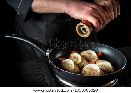 Cooking cutlets on pan by chef hands on black background for copy space text restaurant menu. The chef or cook adds pepper