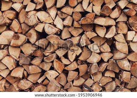 Firewood stacked near wall close-up background. Picture of logs stacked on pile. Wooden texture: neatly laid out woodpile. Wood village natural backgrounds. Concept of country lifestyle. Copy space