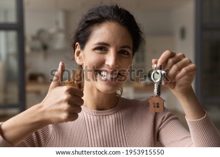 I recommend you. Headshot portrait of happy young latin woman realty buyer look at camera with keys in hand hold thumb up gesture. Satisfied female client speak good about real estate agency service