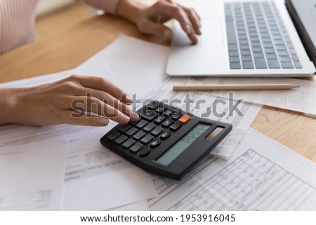 Accounting is an exact science. Close up cropped view of young woman enterpreneur hands doing financial paperwork check money savings sum on bank account calculating goods service price paying bills Royalty-Free Stock Photo #1953916045