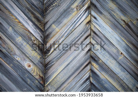 Old unpainted wooden planks in the form of a herringbone pattern. Close-up. Background. Texture.