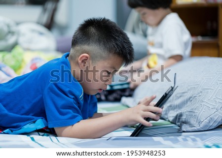 kid watching tablet on the bed, child addicted cartoon
