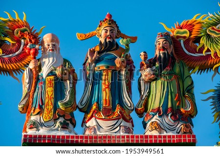 Vibrant colored statues of the three stellar gods of happiness and longevity, Fu Lu Shou, in Chinese mythology, contrasting with a deep blue sky. Tourist spot of Ishigaki island. Royalty-Free Stock Photo #1953949561
