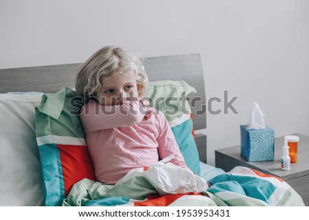 Sick ill kid girl with fever lying in bed at home with flu, fever, running nose. Child coughing sneezing in elbow. Virus cold season flu cornavirus covid-19 illness disease. Medicine and health care
 Royalty-Free Stock Photo #1953953431
