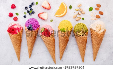 Various of ice cream flavor in cones blueberry ,pistachio ,almond ,orange and cherry setup on white stone background . Summer and Sweet menu concept. Royalty-Free Stock Photo #1953959506