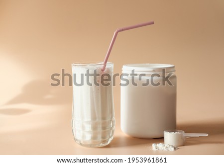 whey drink in a high glass. whey protein vanilla cocktail. a jar with protein powder and a scoop of powder on a table. morning drink for health and beauty. Royalty-Free Stock Photo #1953961861