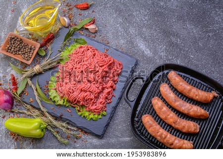 Fresh minced pork and sausage in a natural shell, decorated with garlic, red pepper and dill on a slate stone.Dark texture background.Flat layout.top view.culinary background