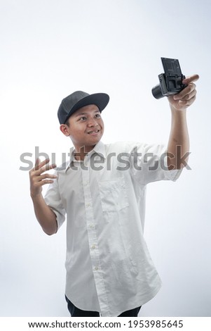 Asian teenager taking a photo of himself with his camera isolated in white background