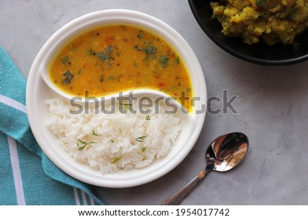 Healthy nutritious Indian comfort food Dal Chawal thali or Dal Rice, also commonly known as Varan bhat in Marathi. Served in two way ceramic plate. Over white background with copy space. Royalty-Free Stock Photo #1954017742