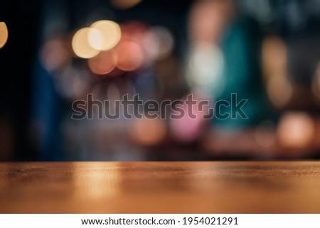 Wood table top on of abstract blurred restaurant lights background.