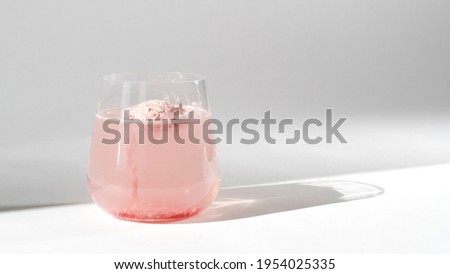 Super food. Glass of natural strawberry collagen protein powder in glass of water for skin regeneration. Trendy food additives. White background with sunlight and deep shadow of glass. Hard sunlight. Royalty-Free Stock Photo #1954025335
