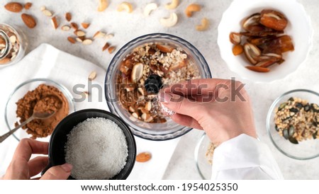 Step by step cooking Energy balls. Step 4 recipe of no bake energy balls. Adding coconut flakes and other ingredients to the blender or food processor. Healthy raw dessert, vegetarian candies. Royalty-Free Stock Photo #1954025350