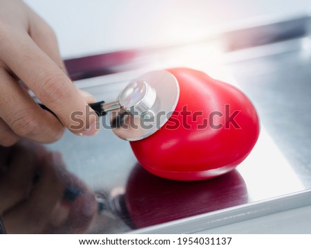 Close up the red heart ball examination with a stethoscope by the doctor's hands on a stainless steel medical tray. Cardiology, healthcare, and medicine concept.