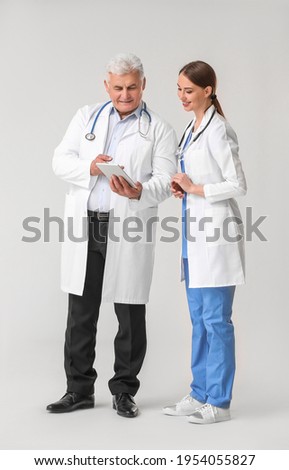 Doctors with tablet computer on grey background