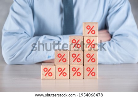 Businessman hand takes a wooden cube block depicting,shown the percentage symbol icon. Interest rate financial and mortgage rates concept